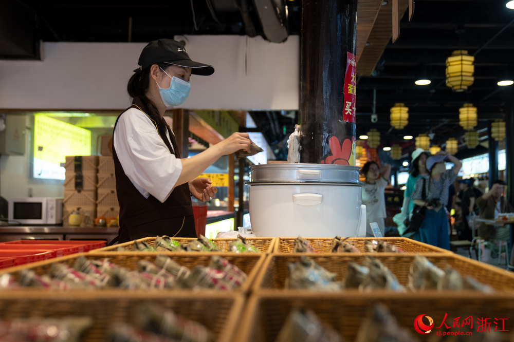 5月26日，端午將至，浙江省嘉興市月河街的一處店鋪內，店員將剛包好的粽子放入鍋中。人民網記者 葛泰佚攝